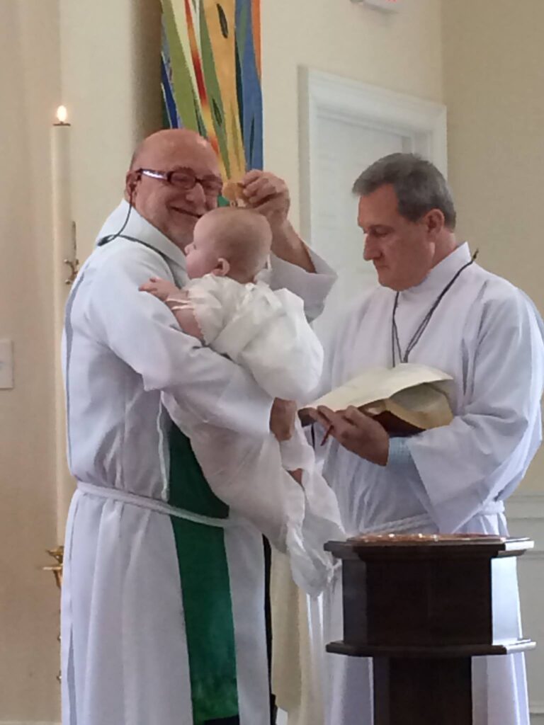 Father Stopfel and Verger Barry Dennis perform a baptism.